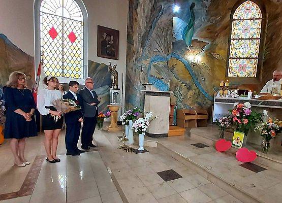 Dyrekcja i uczniowie z kwiatami dla księdza