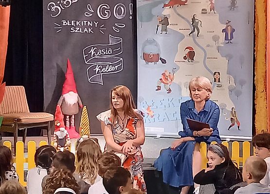 Dzieci siedzą w sali przed sceną, słuchają.