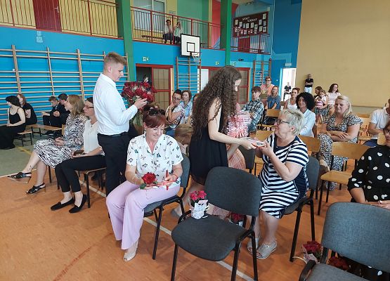 Uczniowie wręczają kwiaty nauczycielom