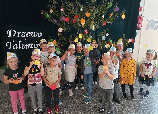 dzieci wieszają kropki na drzewie talentów