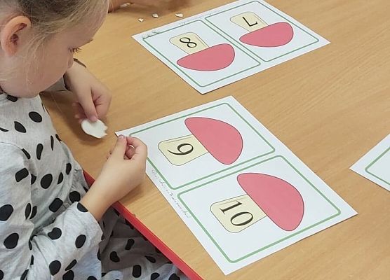 dzieci siedzą przy stoliku i wykonują prace plastyczne