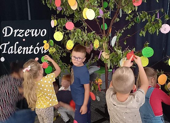 dzieci wieszają kropki na drzewie talentów