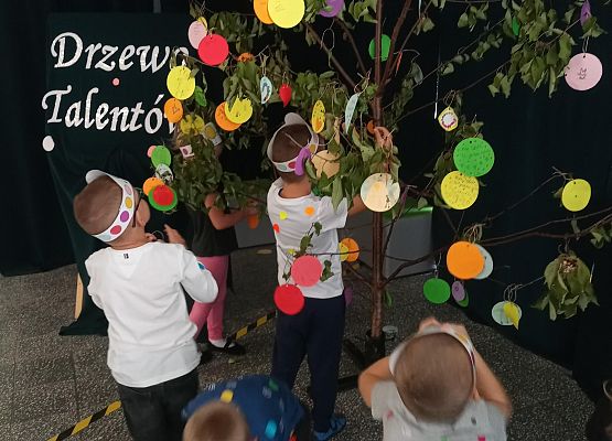 dzieci wieszają kropki na drzewie talentów