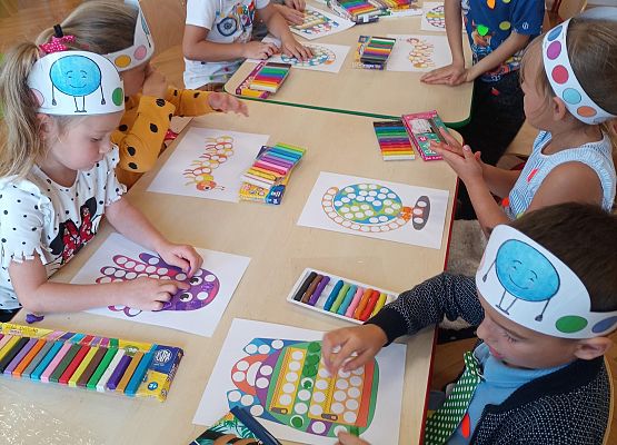 dzieci siedzą przy stoliku i wykonują prace plastyczne
