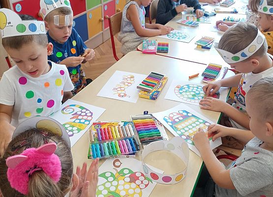 dzieci siedzą przy stoliku i wykonują prace plastyczne