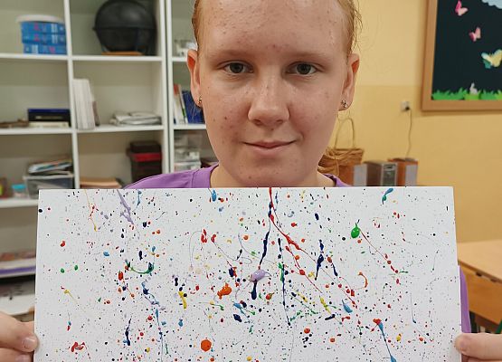 Dziewczynka prezentuje swoją pracę w kropki