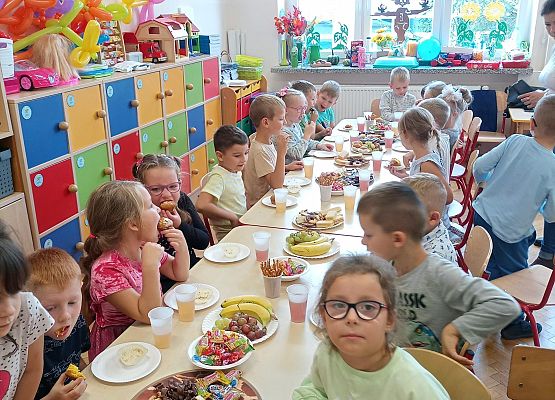 Dzieci siedzą przy stole podczas słodkiego poczęstunku