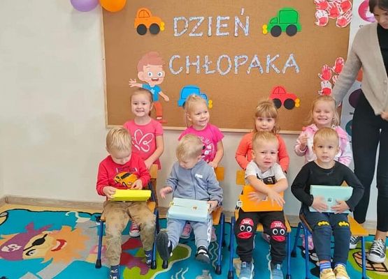 Dzieci i nauczycielka na tle tablicy z napisem dzień chłopaka