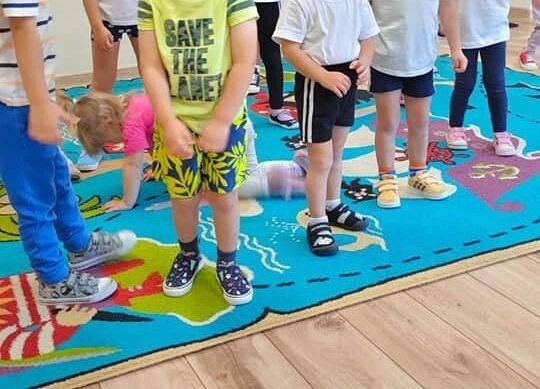 Przedszkolaki w strojach gimnastycznych ćwiczą