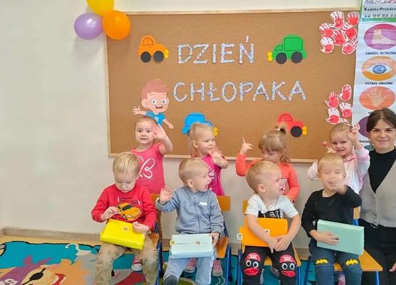 Zdjęcie grupowe przedszkolaków z nauczycielkom. W tle napis dzień chłopaka