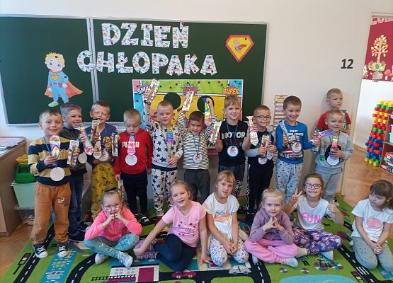 Wspólne zdjęcie dzieci przy tablicy z napisem dzień chłopaka