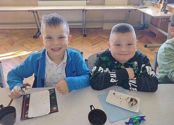 Dwaj chłopcy siedzą przy stoliku podczas słodkiego poczęstunku