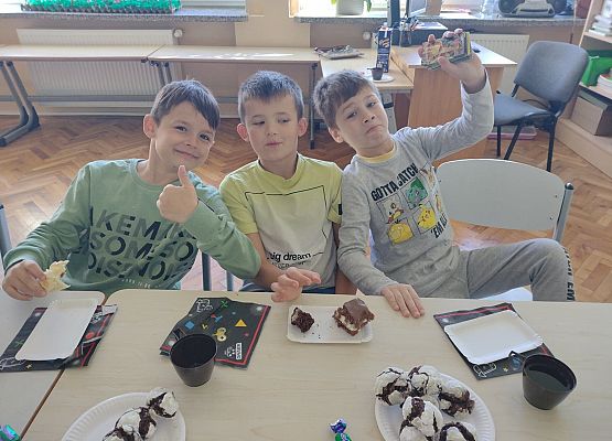 Chłopcy siedzą przy stoliku podczas słodkiego poczęstunku