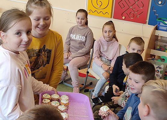 Uczennica częstuje chłopców babeczkami