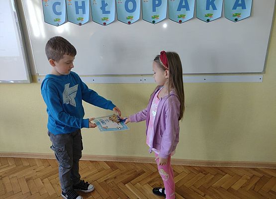 Uczennica wręcza koledze upominek i dyplom
