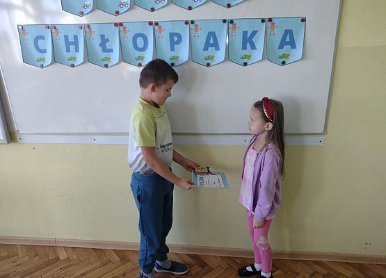 Uczennica wręcza koledze upominek i dyplom