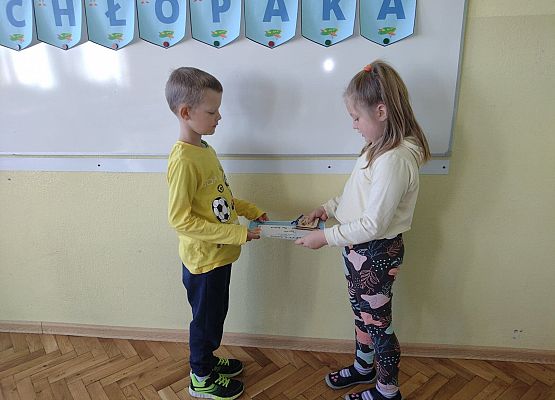 Uczennica wręcza koledze upominek i dyplom