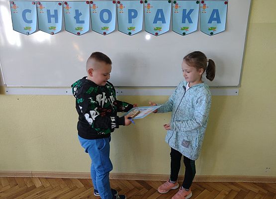 Uczennica wręcza koledze upominek i dyplom