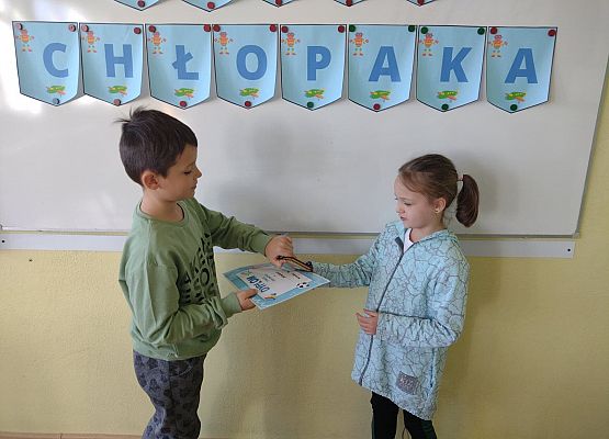 Uczennica wręcza koledze upominek i dyplom