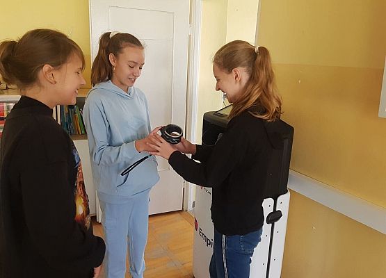 Uczennica przekazuje gogle koleżance.