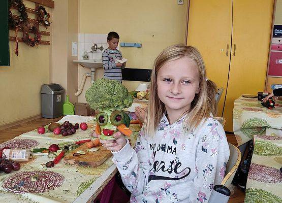 Uczennica prezentuje wykonanego z warzyw stworka