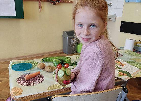 Uczennica prezentuje wykonanego z warzyw stworka