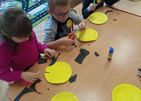 Dzieci wykonują z papieru uśmiechnięte buźki