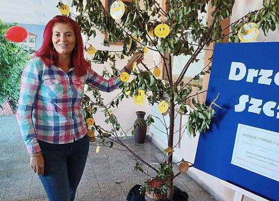 Nauczycielka zawiesza swoją emotikonkę na drzewie szczęścia