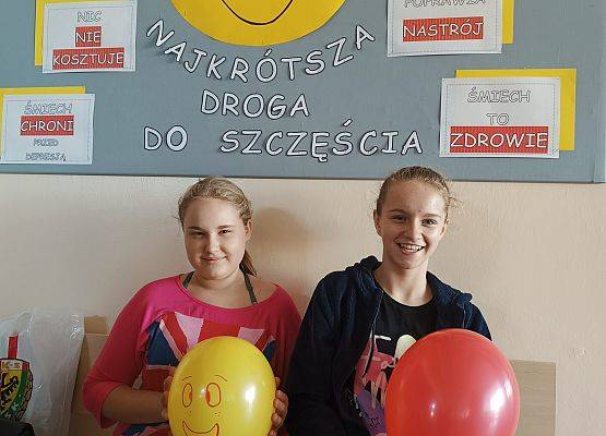 Uczennice siedzą przed tablicą uśmiechu