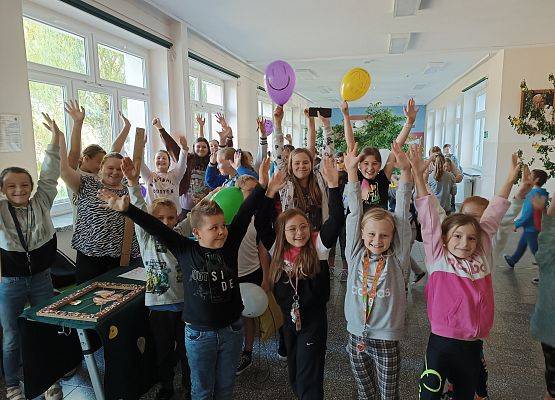 Uczniowie uśmiechnięci przy stoiskach z zabawami.