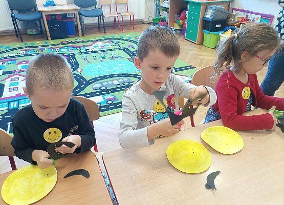 Dzieci wykonują z papieru uśmiechnięte buźki