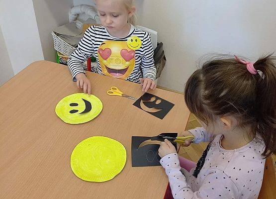 Dzieci wykonują z papieru uśmiechnięte buźki