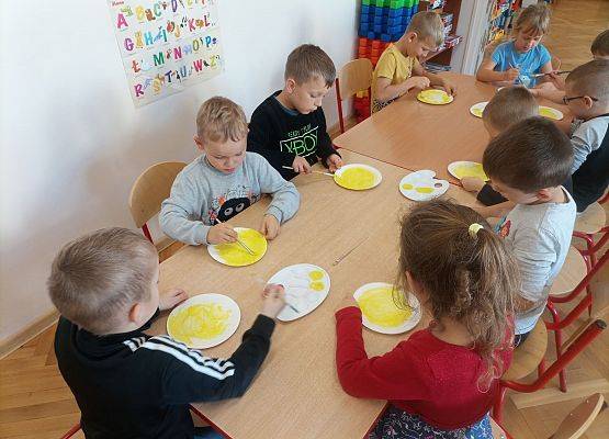 Dzieci wykonują z papieru uśmiechnięte buźki