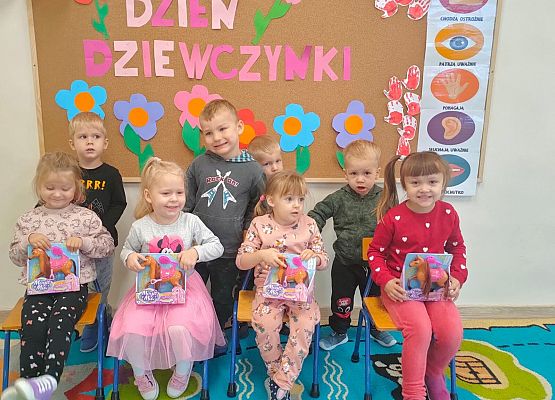 Grupa uśmiechniętych dzieci na tle dekoracji z napisem dzień dziewczynek