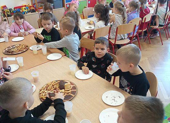 Dzieci siedzą przy stoliku podczas słodkiego poczęstunku