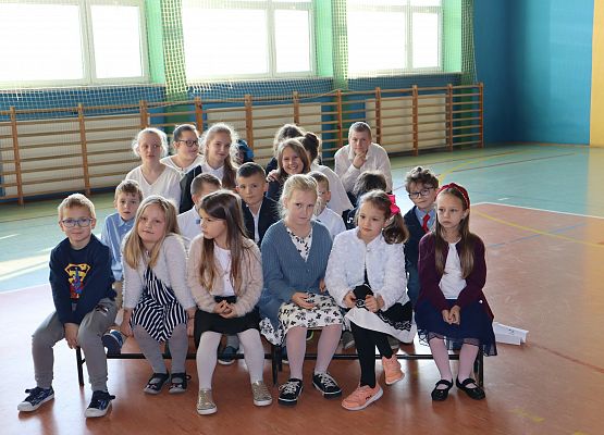 Dzieci siedzą na ławeczkach