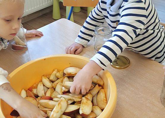 Dzieci przekładają owoce z miski do słoików