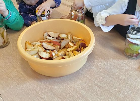 Dziewczynki przekładają owoce z miski do słoików