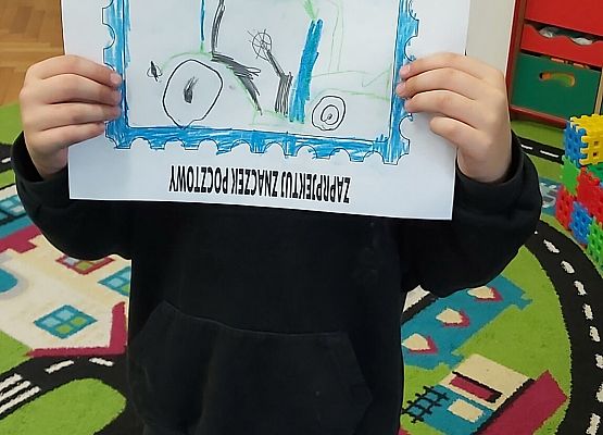 Chłopiec prezentuje swoją pracę plastyczną
