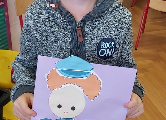 Chłopiec prezentuje swoją pracę plastyczną