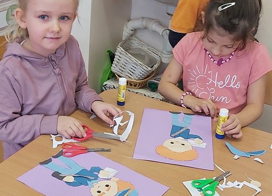 Dzieci siedzą  przy stoliku i wykonują prace plastyczne