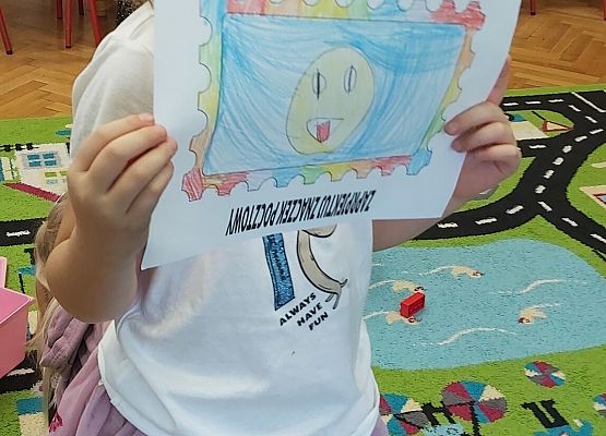 Dziewczynka prezentuje swoją pracę plastyczną