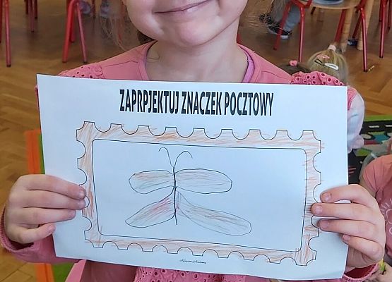 Dziewczynka prezentuje swoją pracę plastyczną