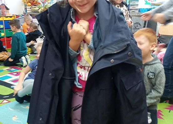 dziewczynka zakłada kurtkę listonosza