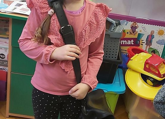 Dziewczynka zakłada torbę listonosza