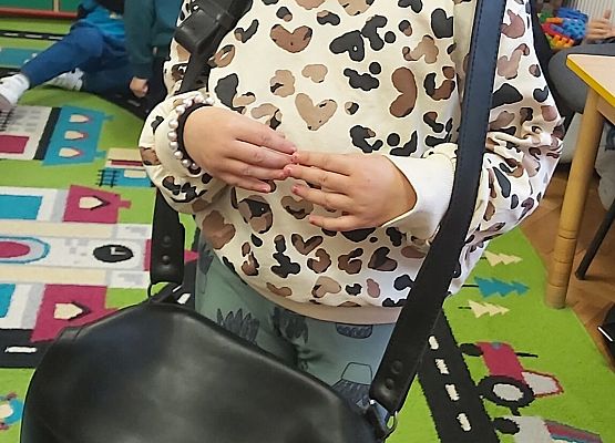 Dziewczynka zakłada torbę listonosza