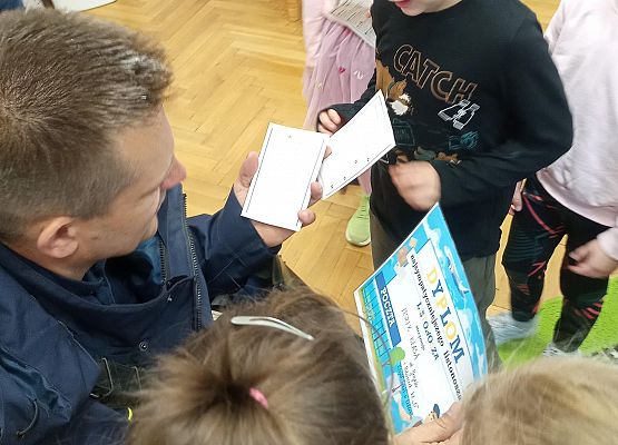 Chłopiec wręcza listonoszowi dyplom