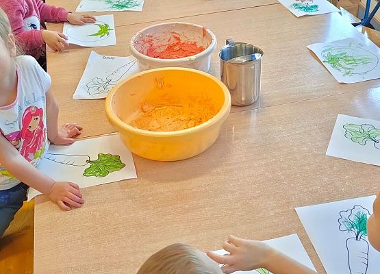 Dzieci siedzą przy stole i wykonują prace plastyczne