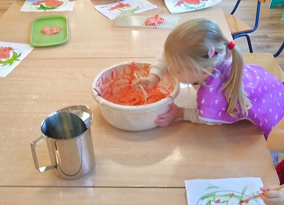 Dziewczynka nabiera z miski masę plastyczną