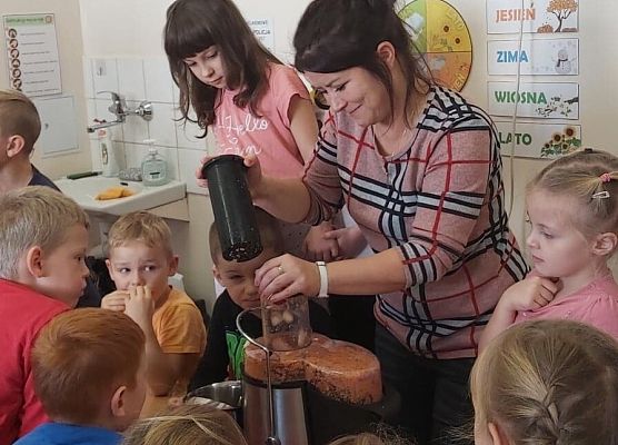 Nauczycielka robi w sokowirówce sok dla dzieci